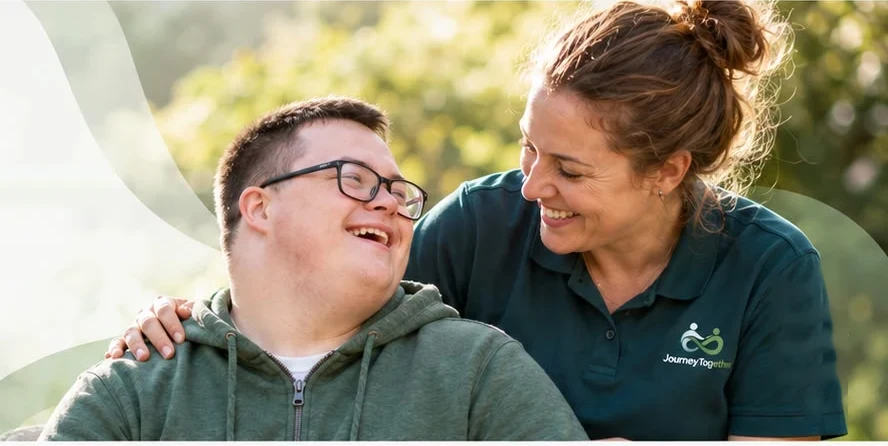 A smiling young man sharing a laugh with his Journey Together support worker outdoors